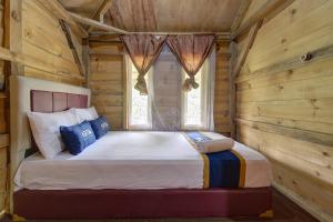 a bedroom with a bed in a log cabin at Kampoeng Regang By BHATARA in Patengan
