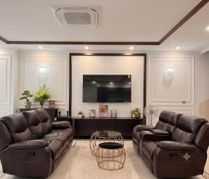 a living room with two leather couches and a tv at Su House Villa in Gò Ba Quần