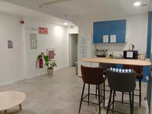 a kitchen with blue cabinets and bar stools at MadVibes Hostel Gran Vía in Madrid