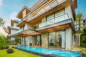 a house with a swimming pool in front of it at Silk Path Dong Trieu Golf Course & Villas in Trại Sưu