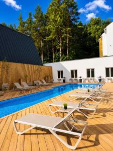 a swimming pool with lounge chairs on a wooden deck at Nykščio Namai & SPA in Anykščiai