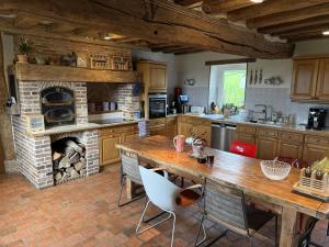 a kitchen with a wooden table and a fireplace at Manoir de Cottentray Charming Manor in Avesnes-en-Bray