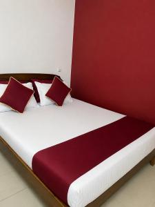 a bed with red and white pillows on it at French Garden Eagle Wings Inn in Trincomalee