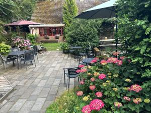 a garden with tables and chairs and flowers and an umbrella at Lille Degnboel Tiny House in Hjørring