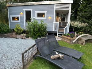 a black chair sitting in the grass in front of a house at Lille Degnboel Tiny House in Hjørring