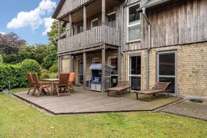a deck with chairs and a table and a grill at Cattle Barn - leben auf dem Hof in Tröndel