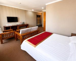 a bedroom with a bed and a desk and a television at Hotel Nomu in Ulaanbaatar