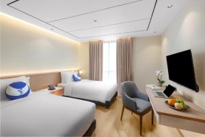 a hotel room with two beds and a desk with a computer at FOX Lite Hotel Majalaya in Bojong