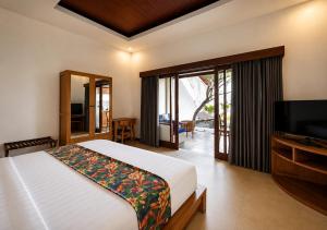 a bedroom with a bed and a flat screen tv at The Haven in Gili Trawangan