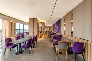 a restaurant with purple chairs and tables and windows at FOX Lite Hotel Majalaya in Bojong