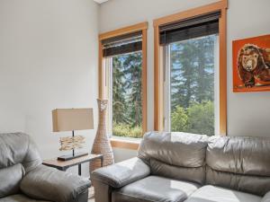 a living room with a leather couch and two windows at Spacious Getaway near Banff with Heated Pool in Canmore
