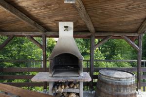an outdoor oven in a wooden structure with a barrel at Mountain Escape house with indoor pool in Fužine