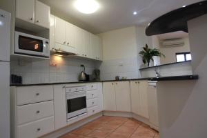 a kitchen with white cabinets and a microwave at Darwin Deluxe Apartments in Darwin