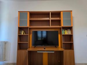 a wooden entertainment center with a tv and shelves at Da Silvia ampio appartamento metro Paradiso in Collegno