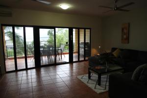 a living room with a couch and sliding glass doors at Darwin Deluxe Apartments in Darwin
