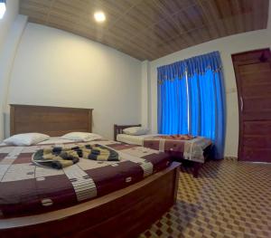 two beds in a room with blue curtains at VRK Adventure Basecamp Sri Lanka in Kitulgala