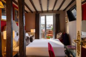 a bedroom with a large white bed and a window at Hotel Des Deux Continents in Paris +81 photos