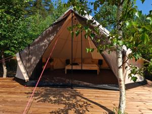 a tent on a wooden deck with a tree at AVOTUPJI GLEMPING telts in Allaži