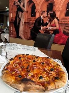 a pizza sitting on top of a table at Hotel Hanul de la Rascruce in Arad +21 photos