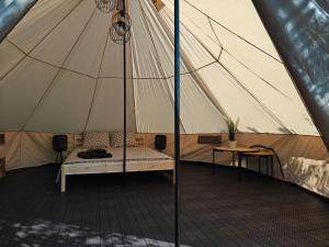 a tent with a bed in the middle of it at AVOTUPJI GLEMPING telts in Allaži +10 photos