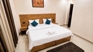 a bedroom with a bed with white sheets and blue pillows at Hariom Stay Rishikesh in Rishīkesh
