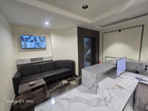 a living room with a couch and a desk with a laptop at Hotel Saffron in Vadodara