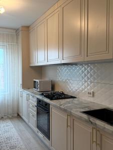 a kitchen with white cabinets and a stove top oven at Erkaiym Guest house in Bokonbayevo