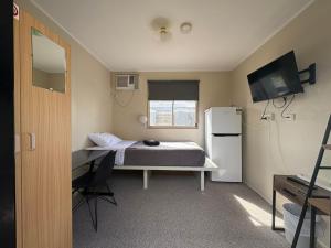 a small room with a bed and a refrigerator at Mycow Accommodation Mackay in Mackay