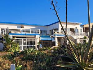 a white house with blue balconies and palm trees at Bentley on the Beach in Umhlanga