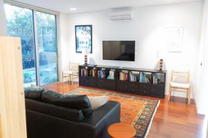 a living room with a black couch and a flat screen tv at Emanjay - Mineral Spa, Million Dollar Views in Mount Martha