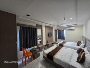 a hotel room with two beds and a chair at Hotel Saffron in Vadodara +8 photos