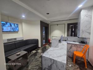 a living room with a black couch and a kitchen at Hotel Saffron in Vadodara