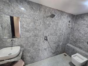 a bathroom with a shower and a sink and a toilet at Hotel Saffron in Vadodara