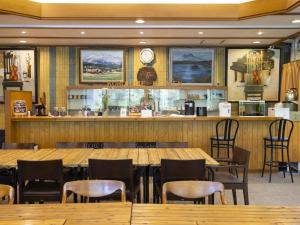 a restaurant with wooden tables and chairs and a counter at 黒姫高原ホテル in Shinano