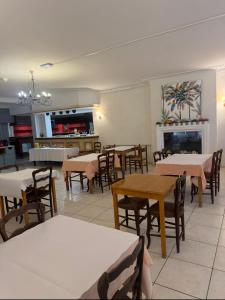 a dining room with tables and chairs and a kitchen at Hôtel Le Robinson in Beaucaire
