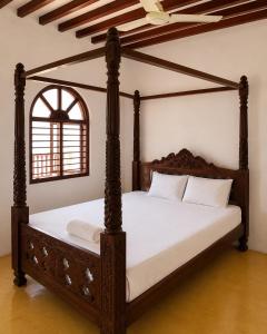 a bedroom with a canopy bed with white sheets at Jannataan Hotel in Lamu