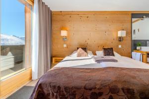 a bedroom with a large bed and a large window at Berghotel Hahnenmoos in Adelboden