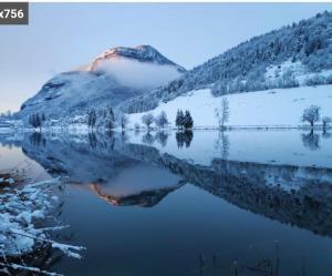 a view of a snow covered mountain and a lake at pas dispo moins de 5 nuits Ecogite du lac in La Thuile