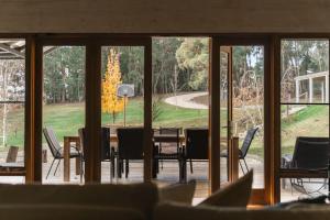 a dining room with a table and chairs looking out onto a yard at Cedar and Stone - Daylesford Region in Glenlyon