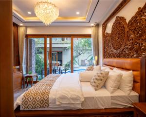 a bedroom with a large bed and a chandelier at MJ Villa Sanur in Sanur