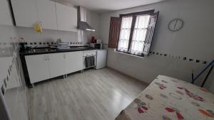 a kitchen with white cabinets and a sink and a window at Alojamiento Oviedo 2 con parking in Oviedo