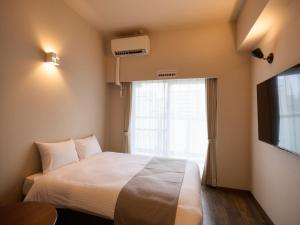 a hotel room with a bed and a window at New Normal Hotel in ASAHIBASHIEKI in Naha