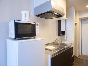a small kitchen with a sink and a microwave at New Normal Hotel in ASAHIBASHIEKI in Naha