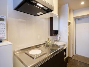 a small kitchen with a sink and a microwave at New Normal Hotel in ASAHIBASHIEKI in Naha +21 photos