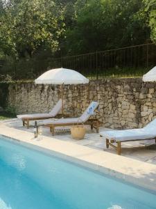 two benches and an umbrella next to a swimming pool at Le Pont de L'orme in Malaucène