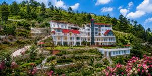 a large building on a hill with flowers at Grand Montis Hotel in Abbottabad