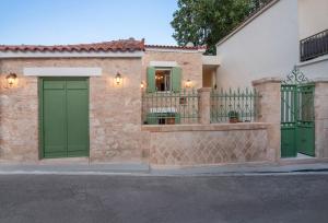 a house with green doors and a fence at Amalthea Guest House in Egina