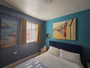 a bedroom with blue walls and a bed and a window at The Hyding Place on George Street in Whitby