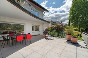 a patio with red chairs and a table on a balcony at Ferien Am Weinberg in Kappelrodeck +60 photos