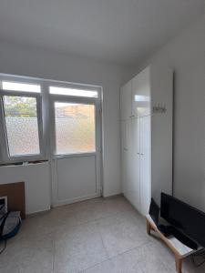 an empty living room with two windows and a television at Zadar Sunhouse Studio with Terrace in Zadar